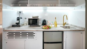 A compact kitchenette with a coffee maker, microwave, sink, and a small refrigerator. - The Daydream Bus Hideaway by Sea N' Rent (Gesher HaZiv)