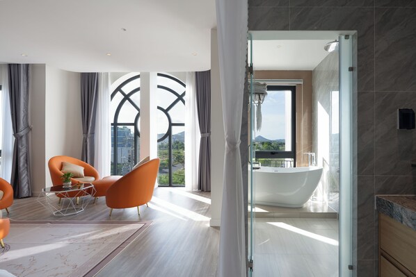 Une salle de bain moderne avec une baignoire sur pieds, de grandes fenêtres et une vue sur l’extérieur.