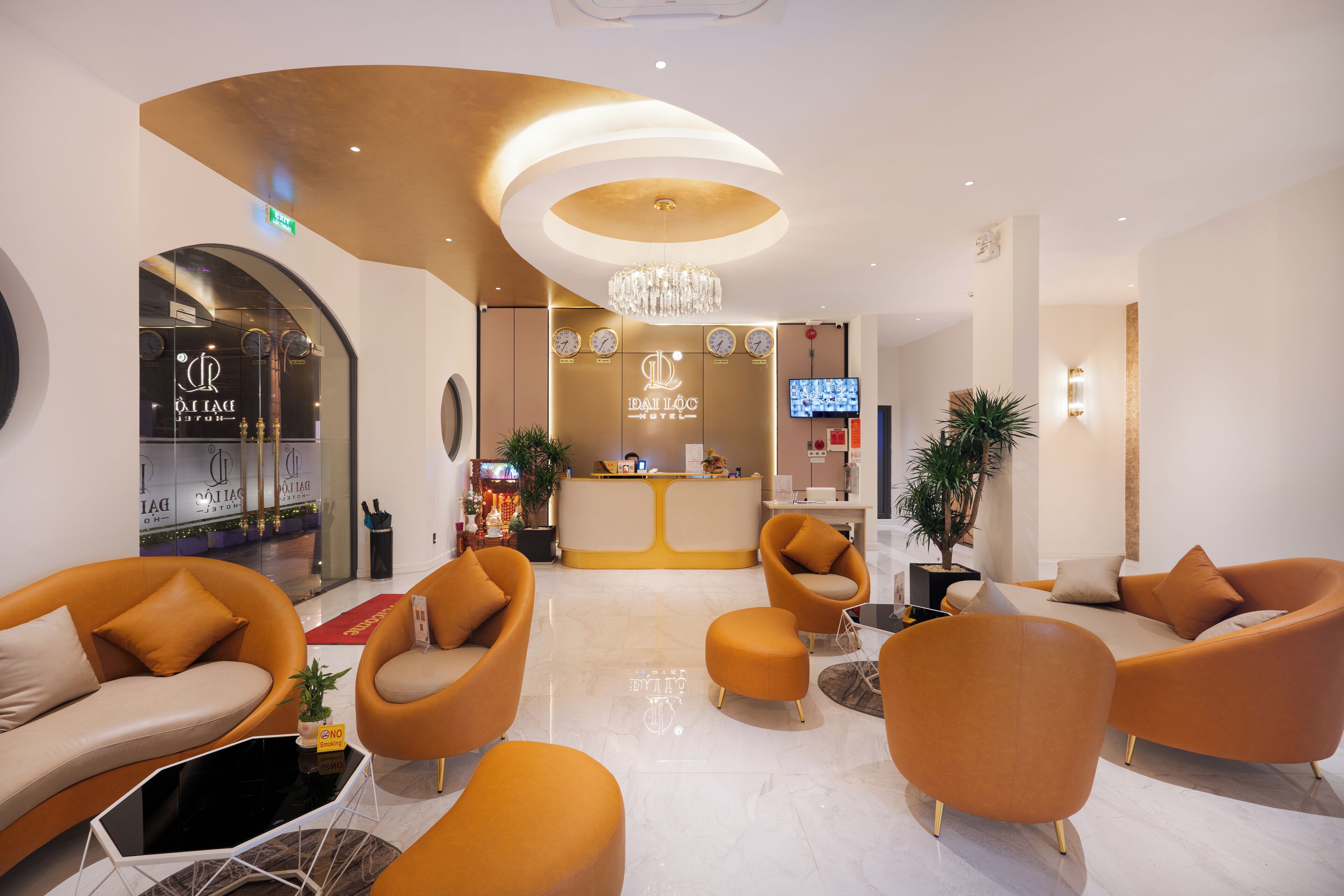 Un hall d’hôtel moderne avec un comptoir d’accueil, un espace salon et un lustre.