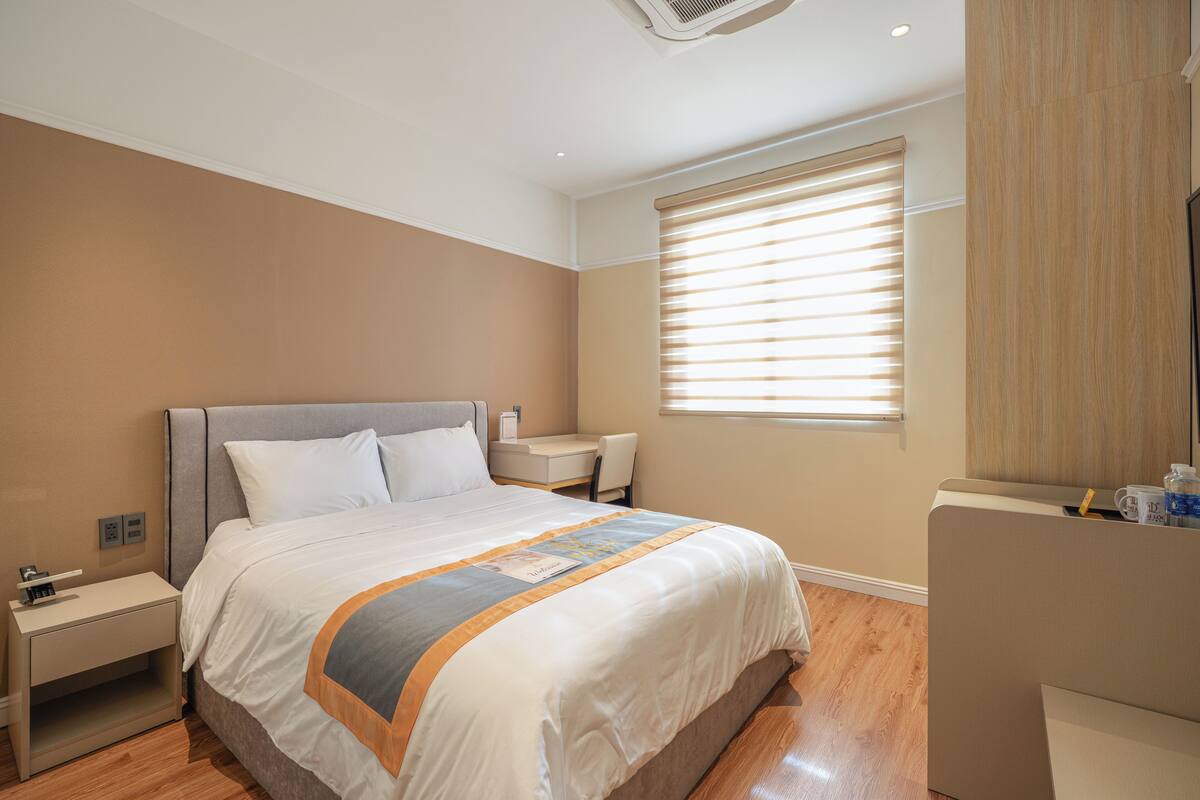 Una camera d'albergo moderna con un letto grande, una scrivania e una finestra con tende.