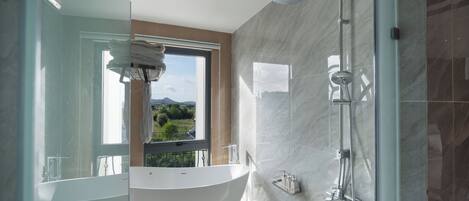 Une salle de bain moderne dotée d’une baignoire sur pieds, d’une douche à l’italienne et d’une grande fenêtre offrant une vue sur l’extérieur.