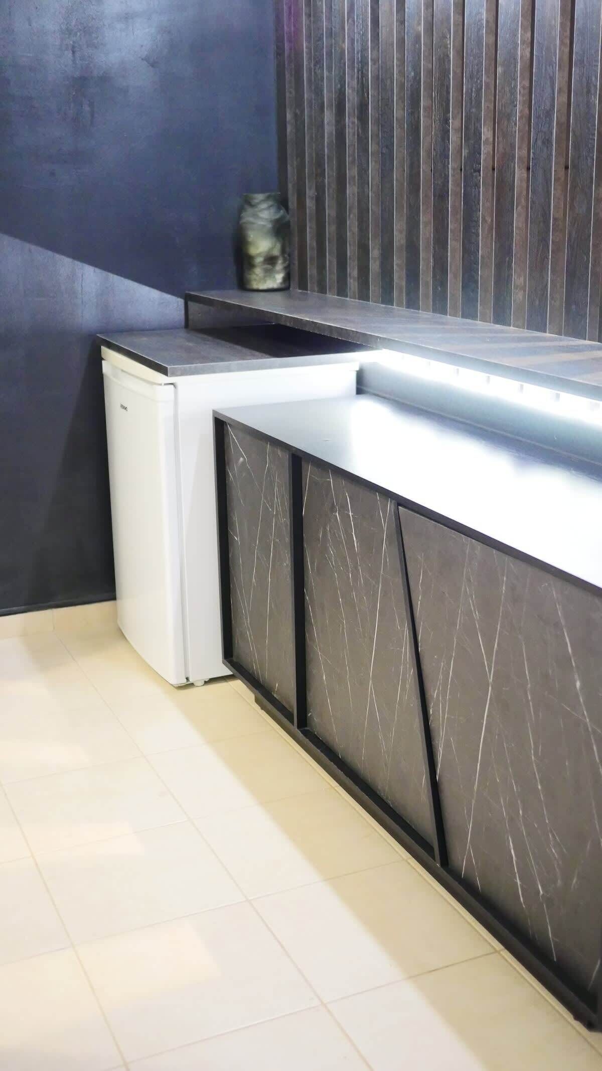A modern kitchen with a white refrigerator, dark cabinets, and a tiled floor.