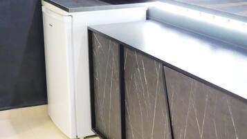 A modern kitchen with a white refrigerator, dark cabinets, and a tiled floor.