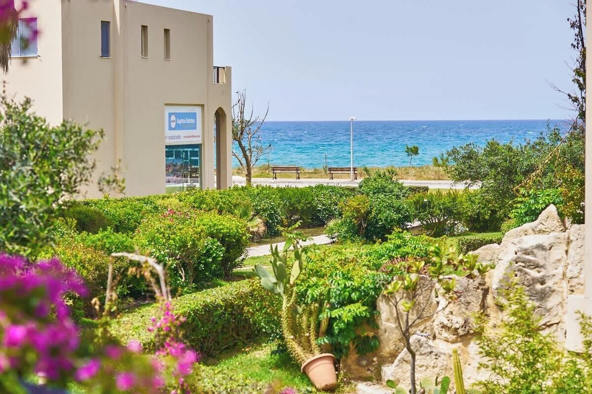 A hotel with a view of the sea, a garden with various plants, and a building with a sign.