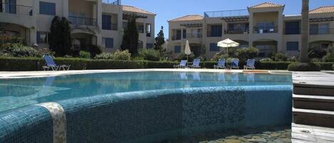 A pool area with lounge chairs and a tiled edge.