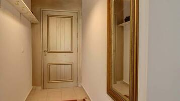 Un pasillo con una puerta de madera, un espejo grande y un tapete estampado.