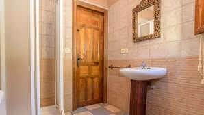 A bathroom with a wooden door, a white sink, and a mirror on the wall.