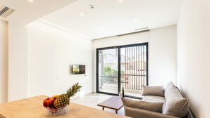 Una sala de estar moderna con una mesa de madera, un sofá y un amplio ventanal corredera que da a un espacio exterior.