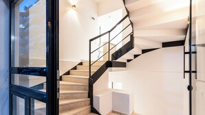 Una escalera moderna con barandillas de vidrio y peldaños color beige, que conduce a un piso superior.