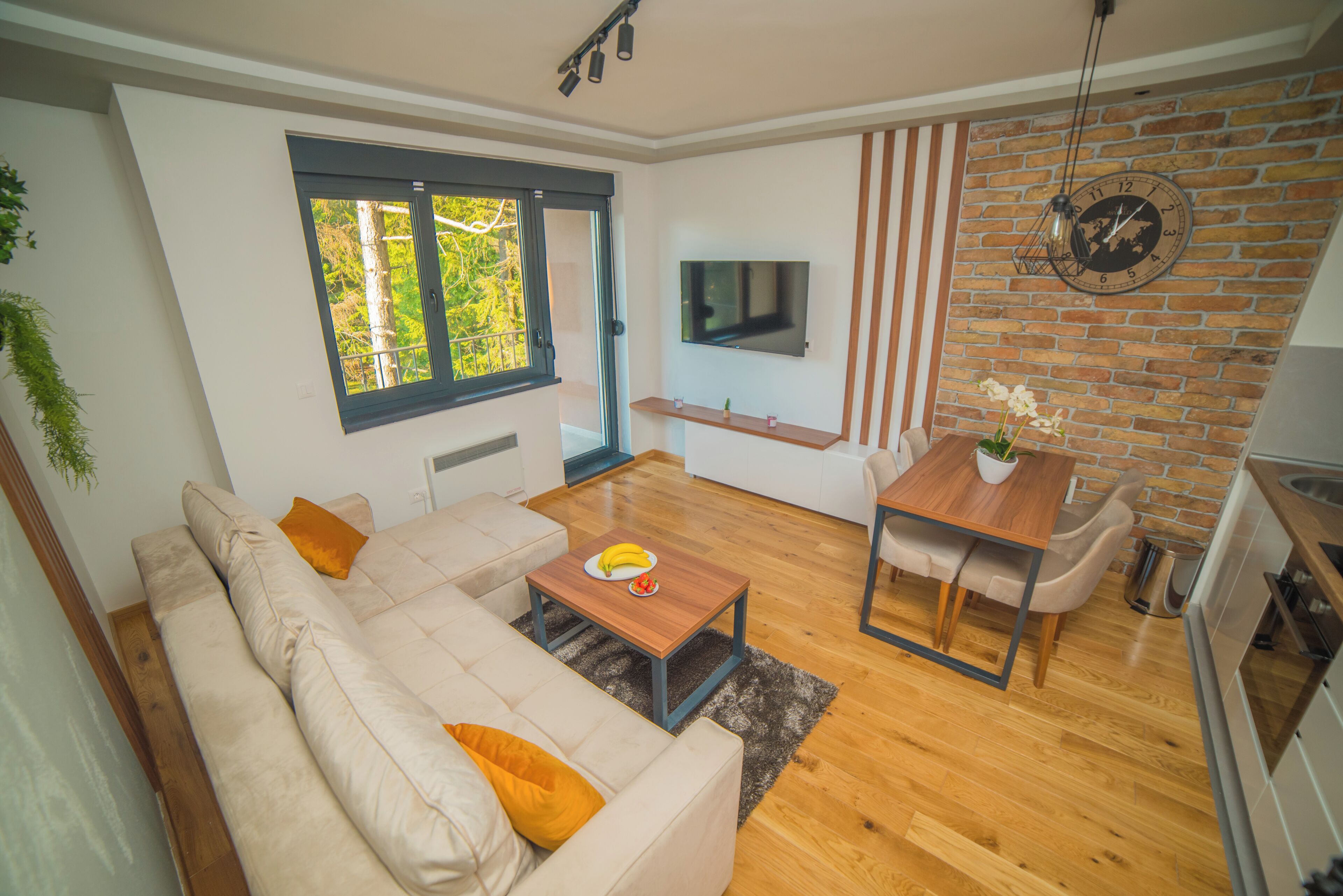 Una sala moderna con sofá, mesa de centro, televisor, mesa de comedor y zona de cocina.