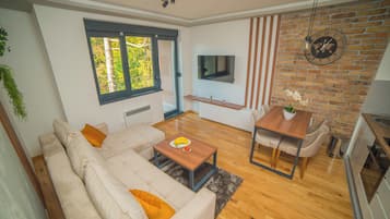 Una sala moderna con sofá, mesa de centro, televisor, mesa de comedor y zona de cocina.