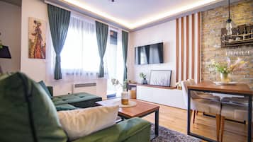 Una sala de estar moderna con un sofá verde, una mesa de centro de madera y un comedor con una mesa y sillas.