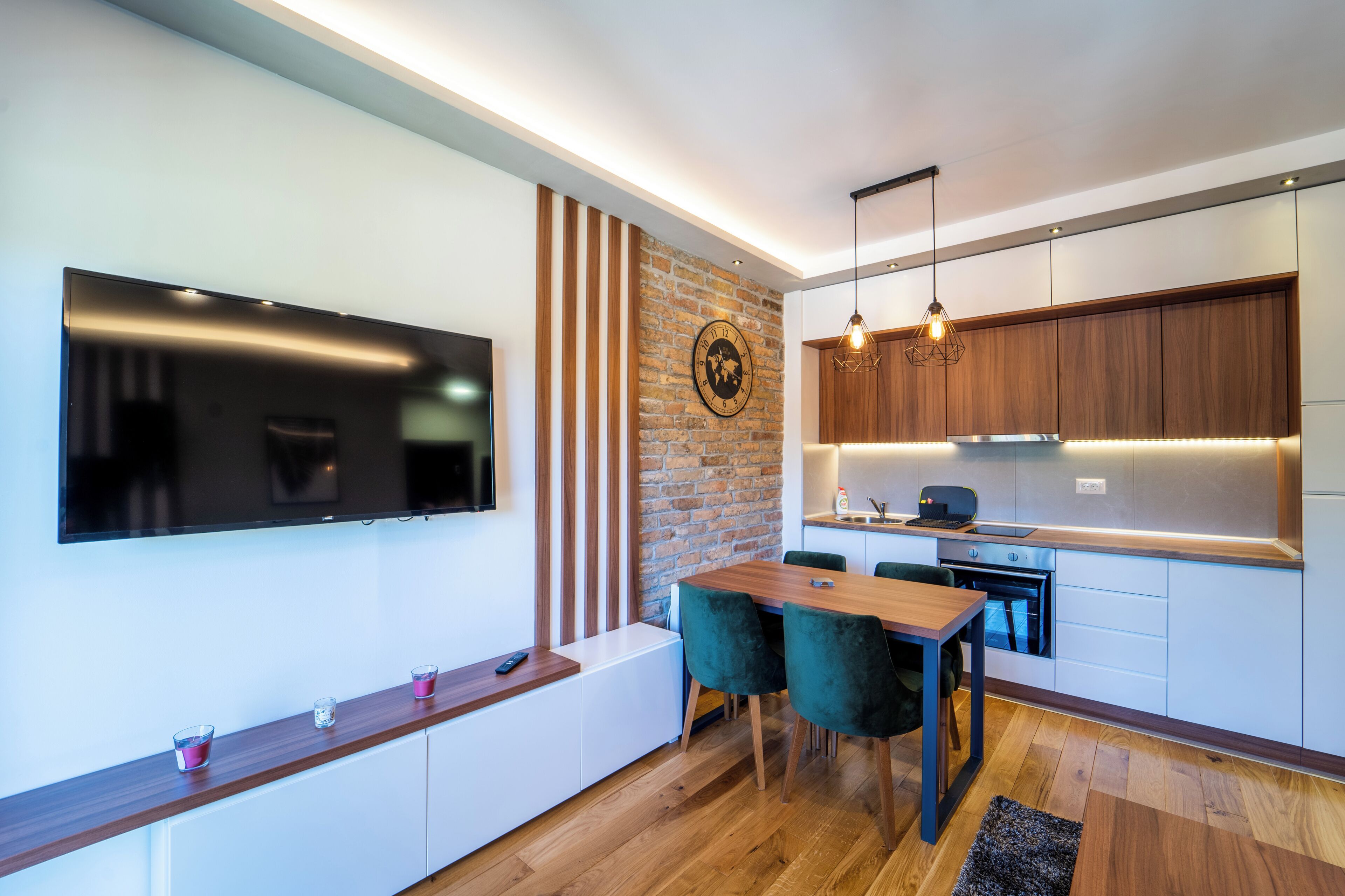 A modern kitchen with a wooden countertop, a built-in oven, and a dining area with two chairs.