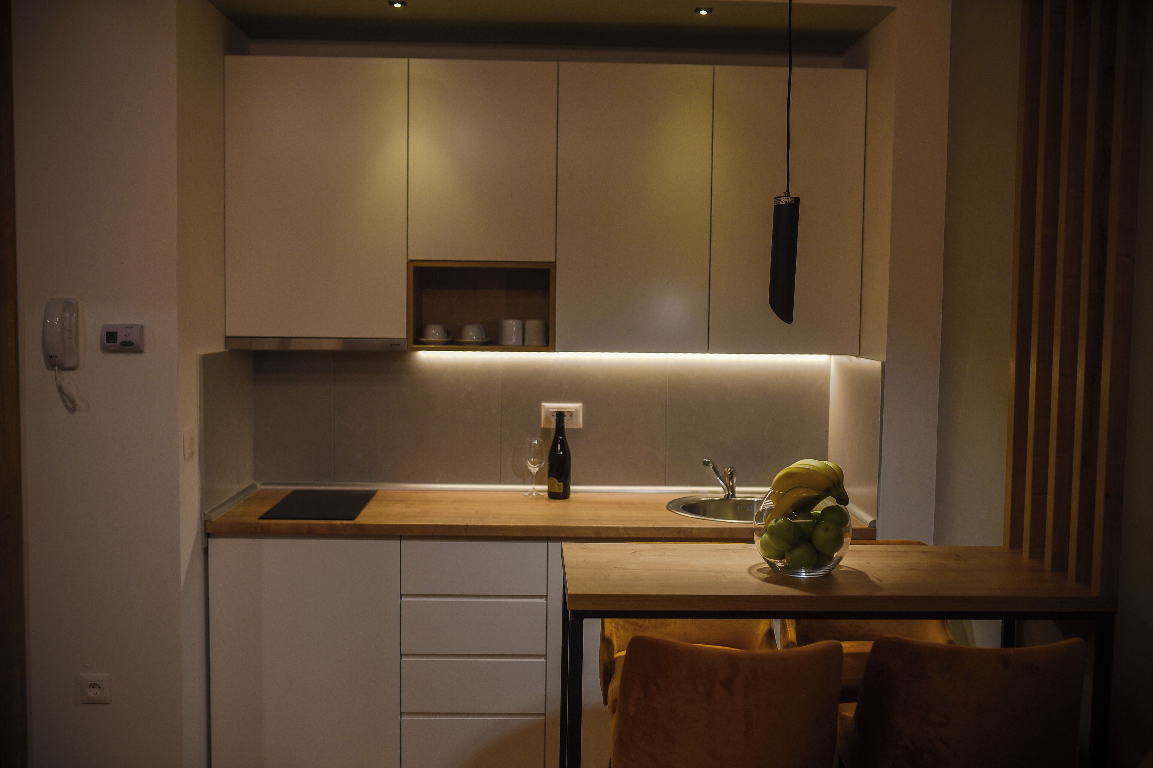 A compact kitchen with a wooden countertop, a built-in sink, and a bowl of fruit on the table.