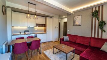 A modern living room with a red sofa, a wooden coffee table, and a dining area with a wooden table and red chairs.