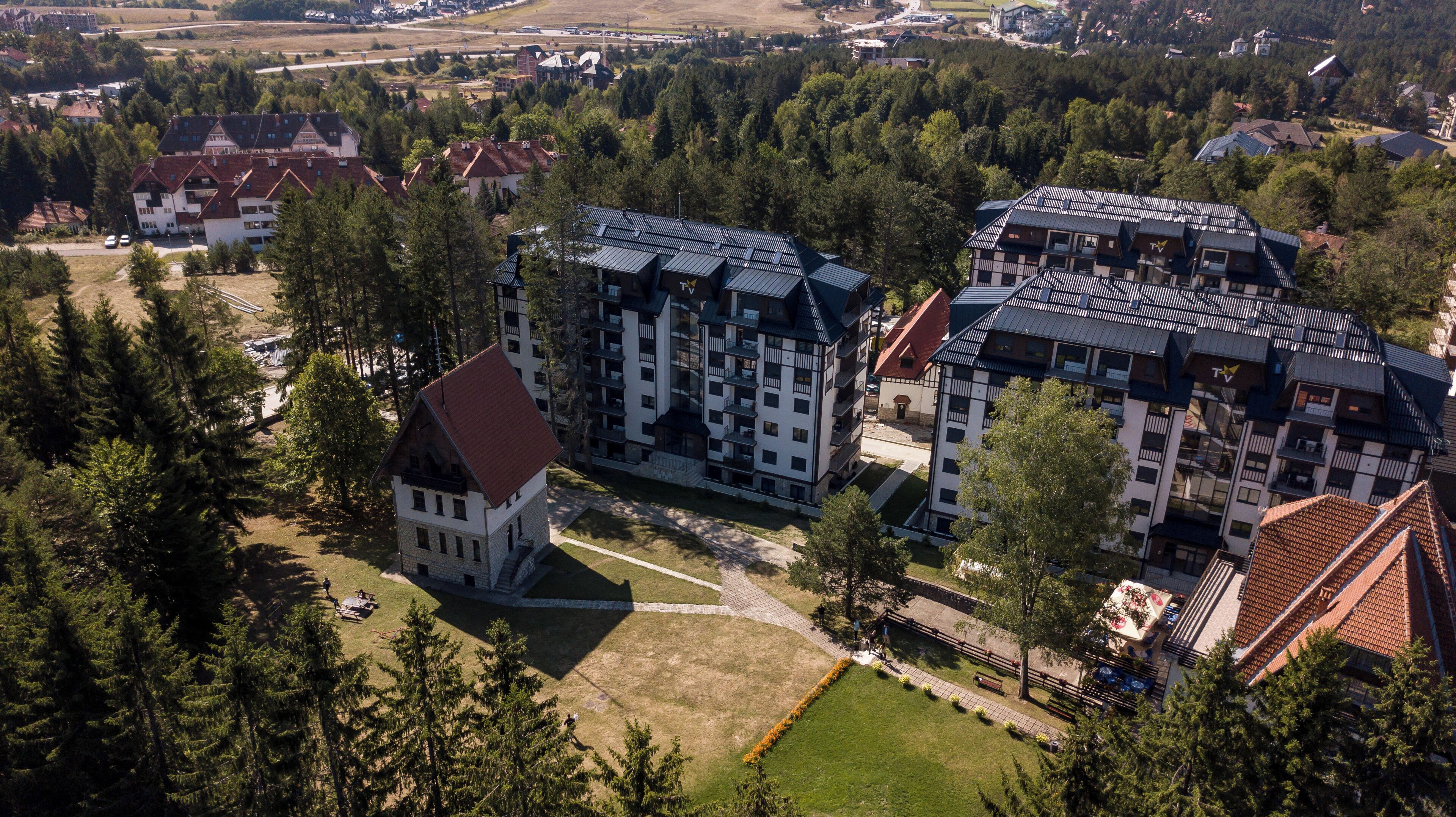 Un hotel de diverses plantes amb un pati central, envoltat per un bosc dens.