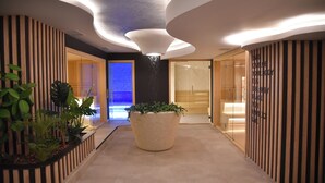 A modern hotel lobby with a central planter, wooden paneling, and a glass door leading to a bathroom.