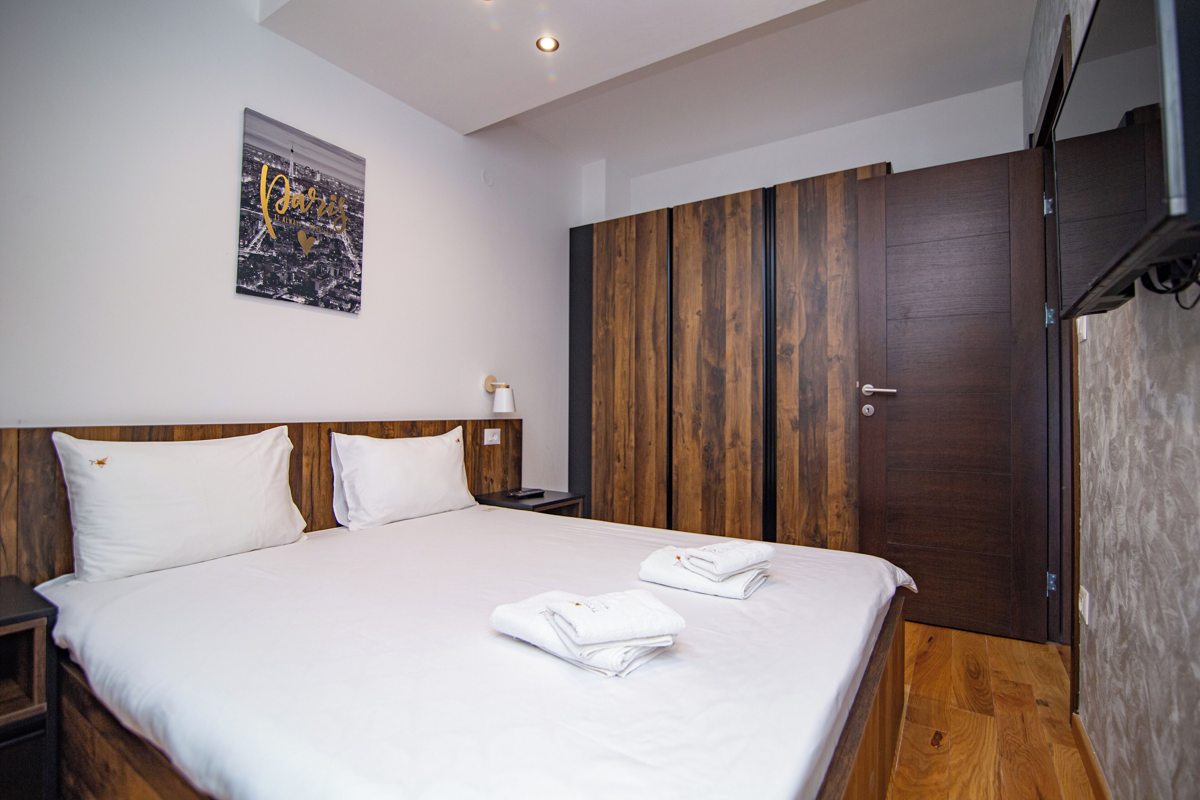 Una habitación de hotel con una cama grande, un armario de madera y un cuadro con una vista urbana.