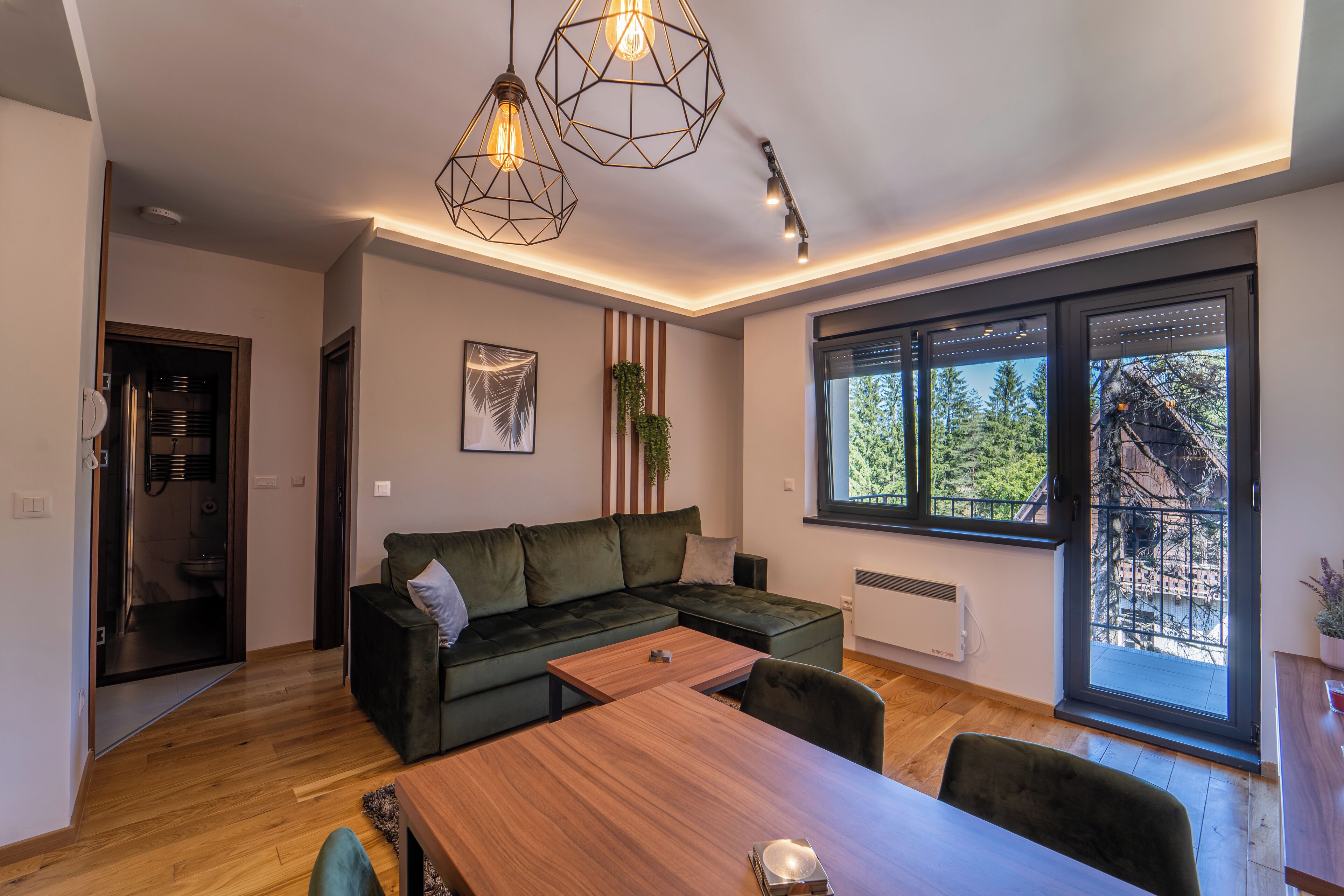 A modern living room with a sectional sofa, a wooden dining table, and pendant lighting.