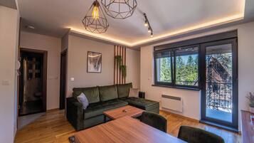 Una sala de estar moderna con un sofá seccional, una mesa de comedor de madera e iluminación colgante.