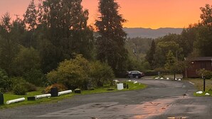 Um estacionamento com vista para o pôr do sol, cercado por árvores e um edifício ao fundo.