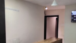A reception desk with a wooden finish, a ceiling light, and a door leading to another room. - WIND FLOWER (Mumbai)
