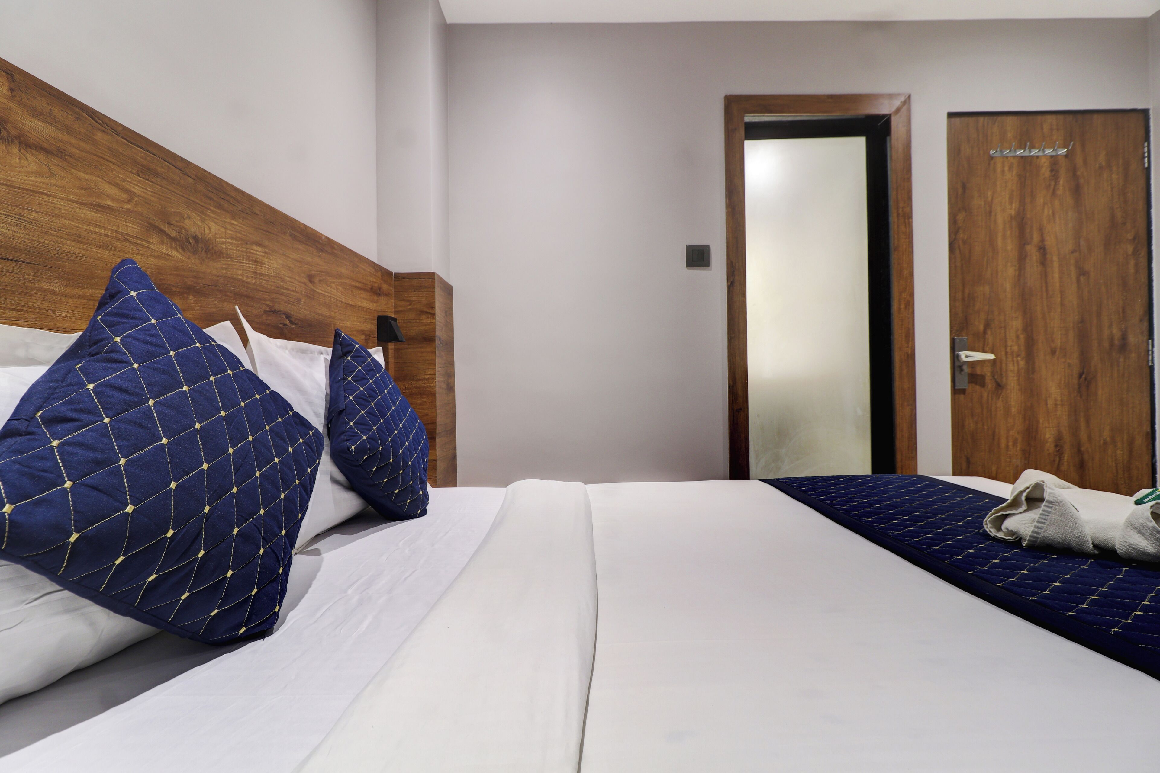 Ein Hotelzimmer mit einem hölzernen Kopfteil, zwei Betten und einer Tür.