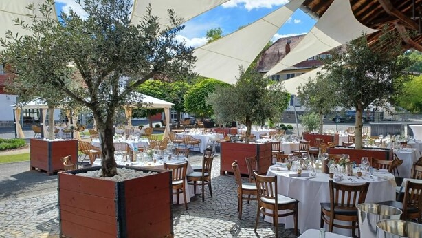 An outdoor dining area with tables and chairs, surrounded by trees and covered by large white canopies. - Hotel Gutshof (Herborn)
