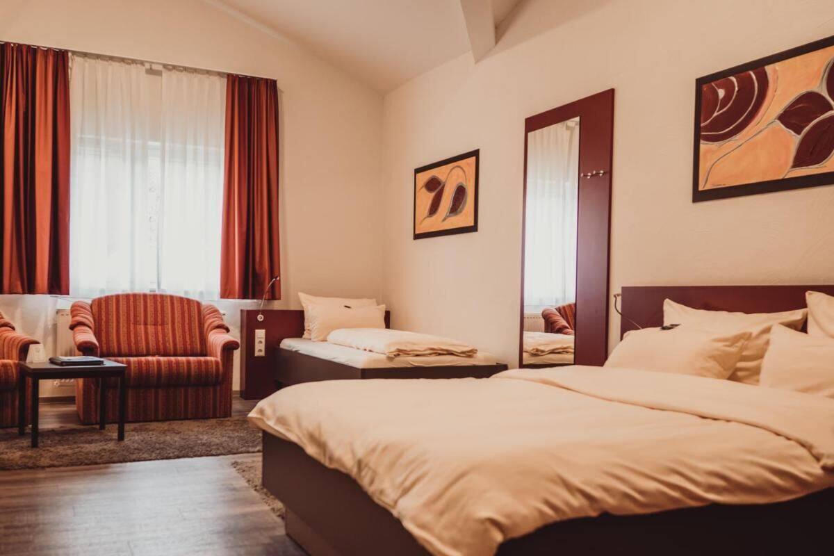 Ein Hotelzimmer mit einem großen Bett, einem Sessel, einem kleinen Tisch und Bildern an den Wänden.