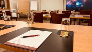 A conference room with a table set for a meeting, a projector screen, and a whiteboard in the background. - Hotel Gutshof (Herborn)