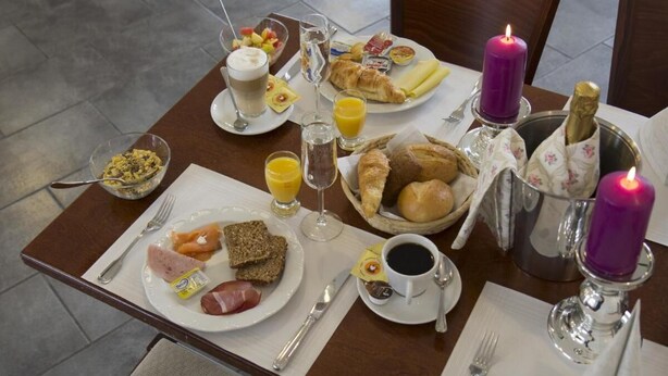 A breakfast table with various food items, drinks, and candles. - Hotel Gutshof (Herborn)
