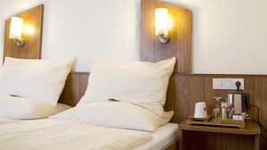 A hotel room with two beds, each with white linens and pillows, and wooden headboards with wall-mounted light fixtures. - Hotel Gutshof (Herborn)