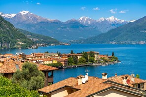 A lakeside town with buildings, a dock, and mountains in the background.