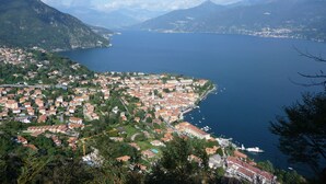 A coastal town with a dense cluster of buildings, a marina with boats, and a mountainous backdrop. - Casa Mia Menaggio (Menaggio)