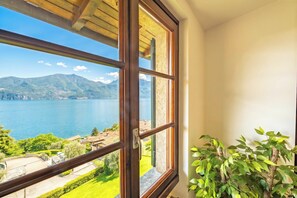 A room with a large window offering a view of a lake and mountains.