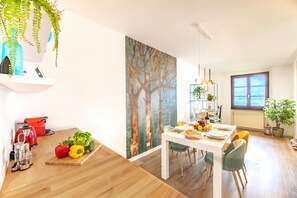 A modern dining area with a wooden table, chairs, and a painting of trees.