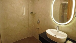 A modern bathroom with a large mirror, a sink, and a shower. - Hotel Naveena Grand (Hyderabad)