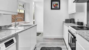 A modern kitchen with white cabinetry, a built-in oven, and a microwave.