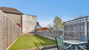 A backyard with a wooden fence, a small shed, and a table with chairs.