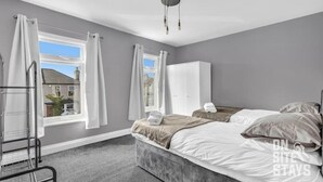 A bedroom with a bed, a wardrobe, and a window with curtains.