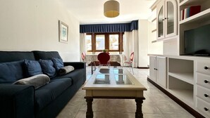 Una sala de estar con sofá, una mesa de comedor y un mueble para televisión.