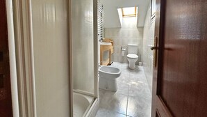 Un baño estrecho con inodoro, bidé y lavamanos pequeño.
