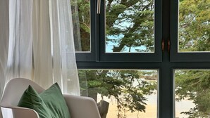 Una habitación moderna con una silla blanca y vistas a árboles a través de un ventanal grande.