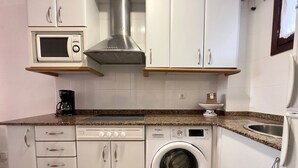 Une cuisine compacte équipée d’un four à micro-ondes, d’une machine à café, d’un lave-linge et d’un évier.