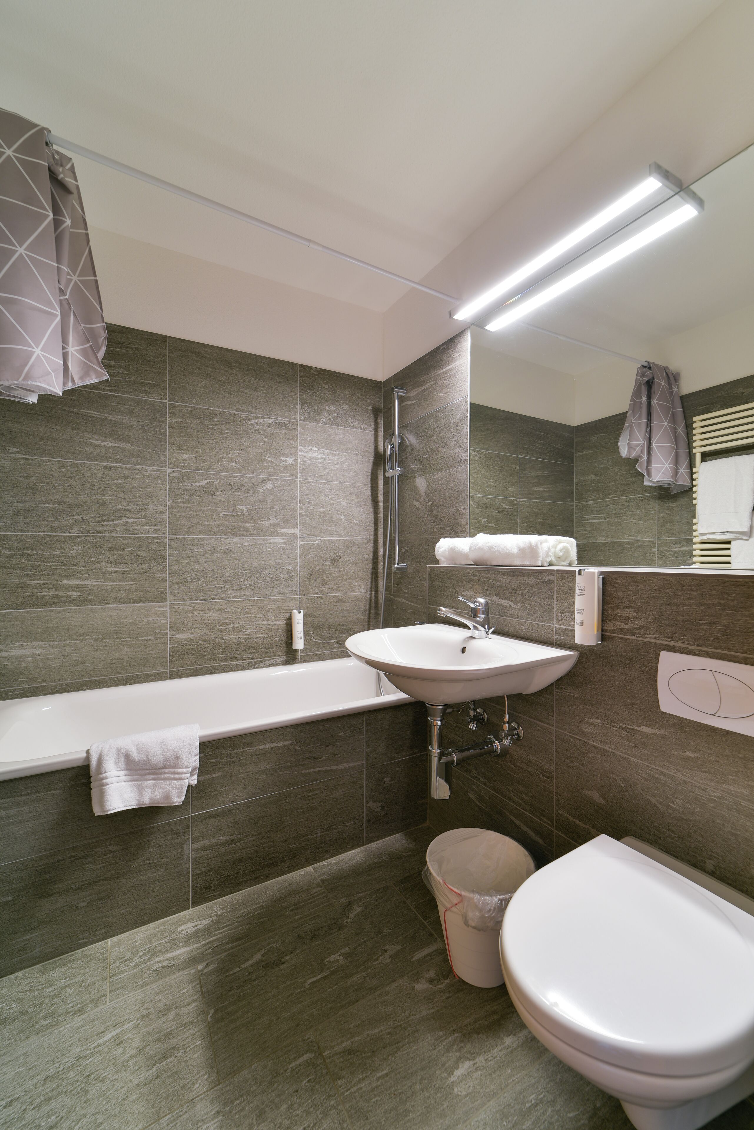 A modern bathroom with a bathtub, sink, and toilet.