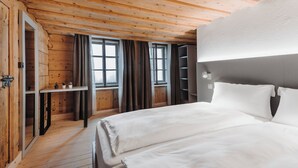 Een slaapkamer met houten lambrisering, een bed, een bureau en een boekenkast.