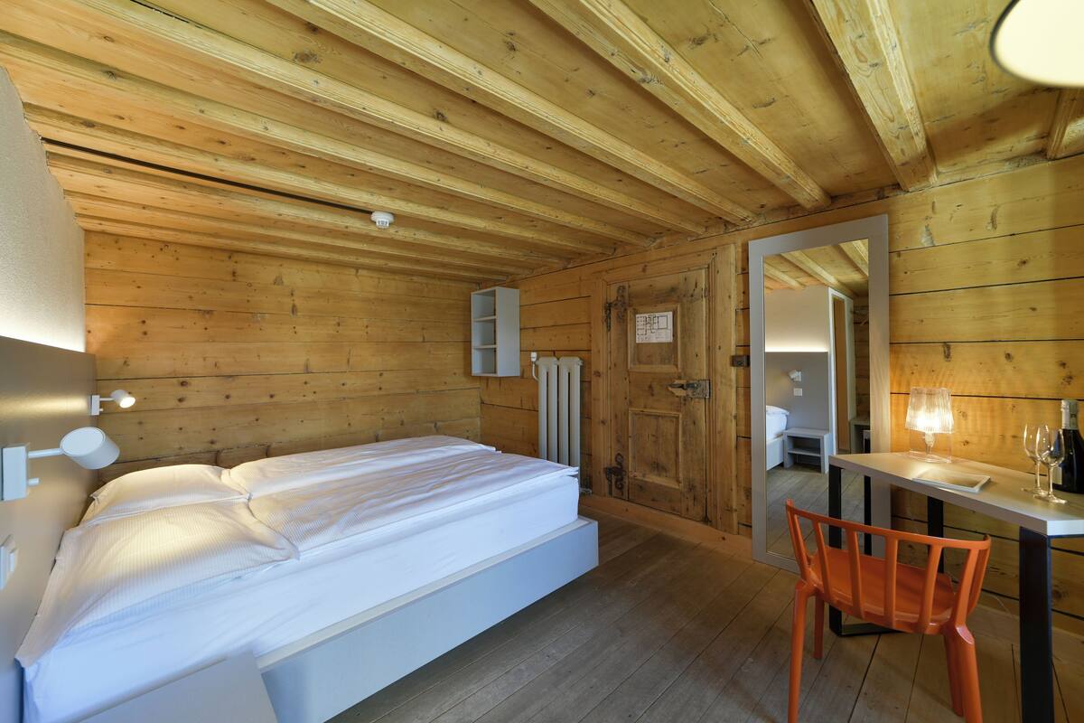 Une pièce en bois avec un lit, une table et une chaise.