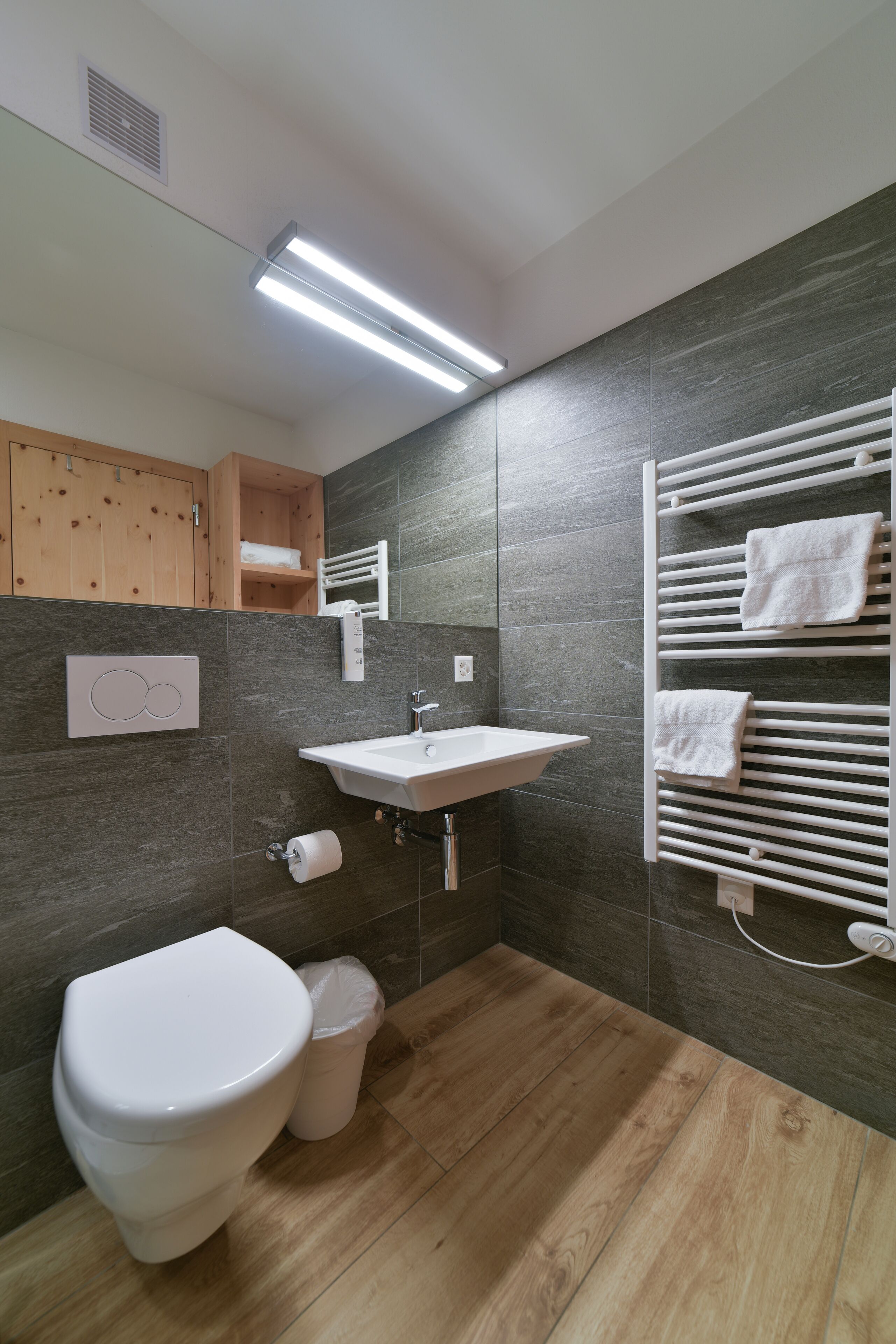 A modern bathroom with a white toilet, sink, and towel rack.