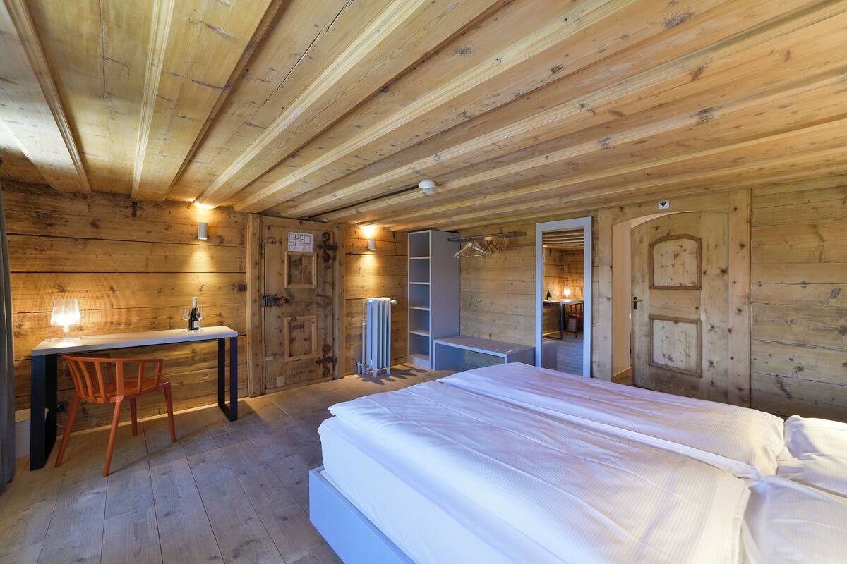 Une chambre dans une cabane en bois, avec un lit, un bureau et une chaise.