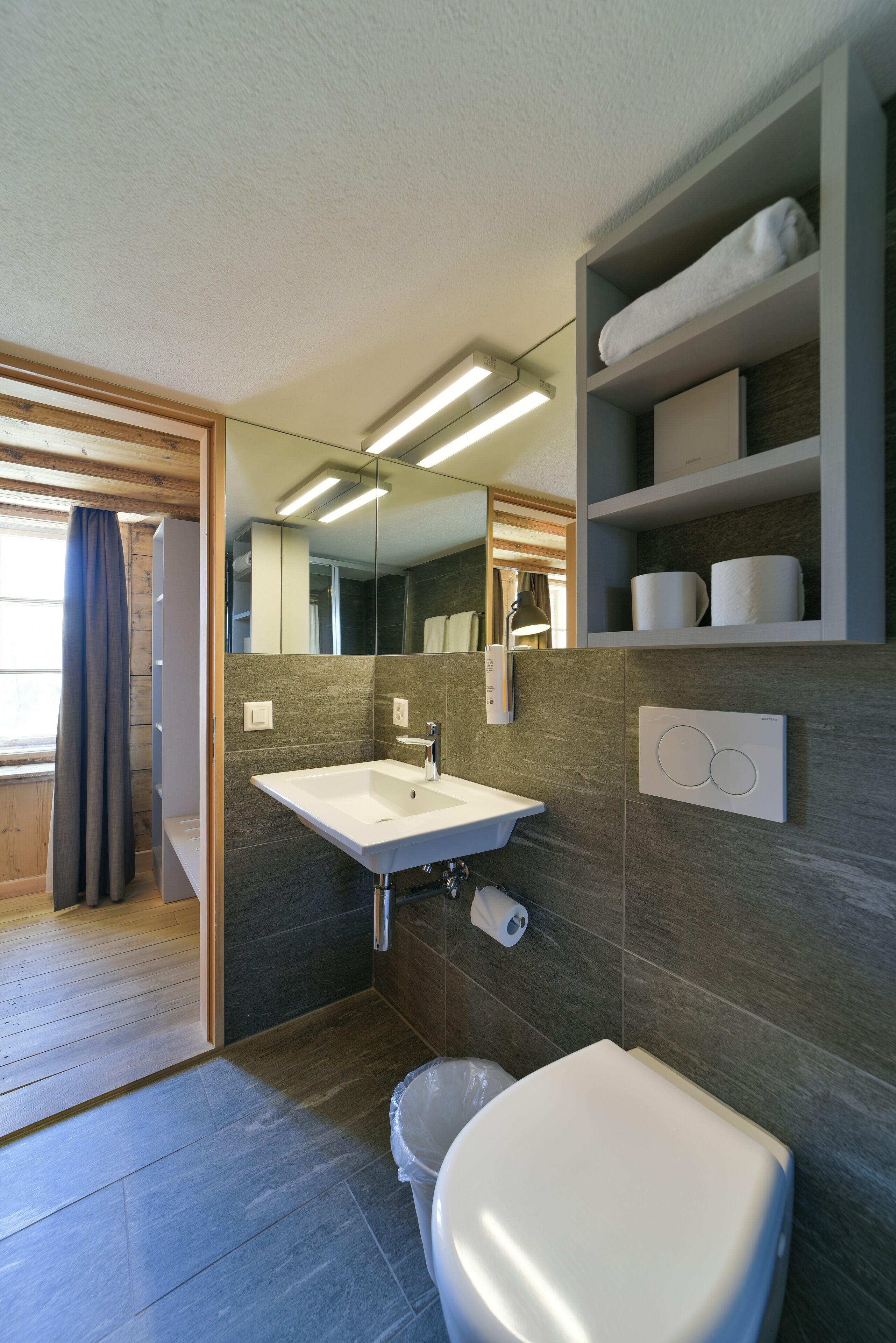 Een moderne badkamer met een wastafel, toilet en inbouwplanken.